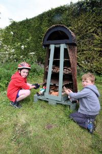 two children Boys helping to fill the ‘Bug Hotel’ with willow and bark.